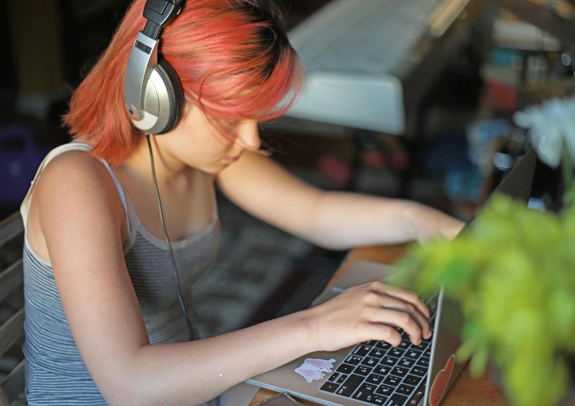 Ung pige sidder og kigger opslugt på sin computer mens hun har høretelefoner på.